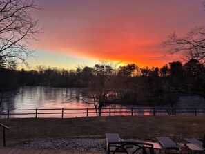 Une vue sur le lac, avec une terrasse en bois, des tables de pique-nique et une clôture.