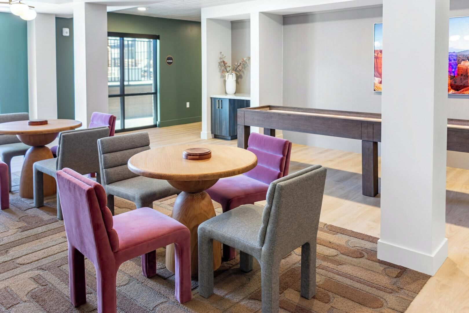 Un área de estar moderna con mesas redondas y sillas acolchadas, una mesa de billar y vistas al exterior.