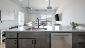 A modern kitchen with a large island, stainless steel appliances, and a view to the outside. - Landing | Stunning 1BD, Pool, Courtyard (Salt Lake City)