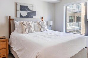 Hotelkamer met een groot bed, nachtkastje, lamp en uitzicht.