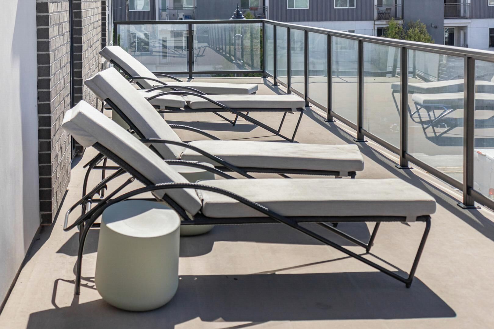 Une terrasse sur le toit, avec des chaises longues et une table ronde.