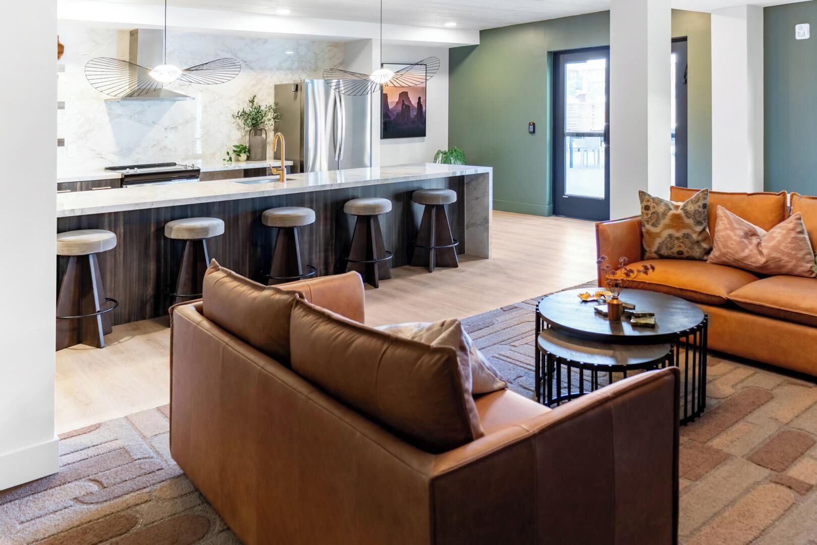 A modern kitchen with a bar area, a leather sofa, and a round coffee table.