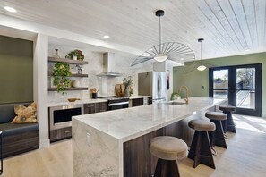 A modern kitchen with a marble countertop, stainless steel appliances, and a central island with stools. - Landing | Incredible 1BD, Gym, Clubhouse (Salt Lake City)