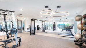 Ett modernt gym med olika typer av träningsutrustning, stora fönster och en minimalistisk design.