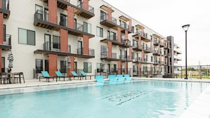 Un immeuble d’appartements moderne doté d’une piscine, d’un espace extérieur aménagé et de balcons.