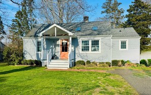 A single-story house with a front porch, a chimney, and a number '26' on the door.
