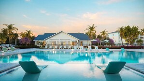 A swimming pool with lounge chairs and a building with a sloped roof in the background. - Landing | Stylish 2BD, Pool (Tice)