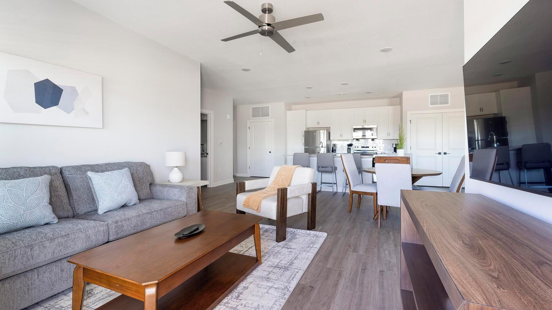 Een moderne woonkamer met een bank, salontafel en een eethoek met stoelen en een tafel.