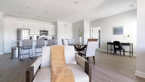 Eine moderne Wohnung mit Essbereich, Küche und Wohnzimmer mit Sofa.