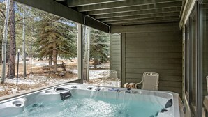 Un jacuzzi con vista a árboles y una terraza de madera.