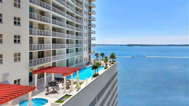 A high-rise hotel with a rooftop pool, multiple balconies, and a view of the sea. - Sky-High Luxury 1BR with Brickell City & Bay Views (Miami)