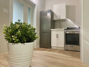 A compact kitchen with white cabinets, a stainless steel refrigerator, and an oven.