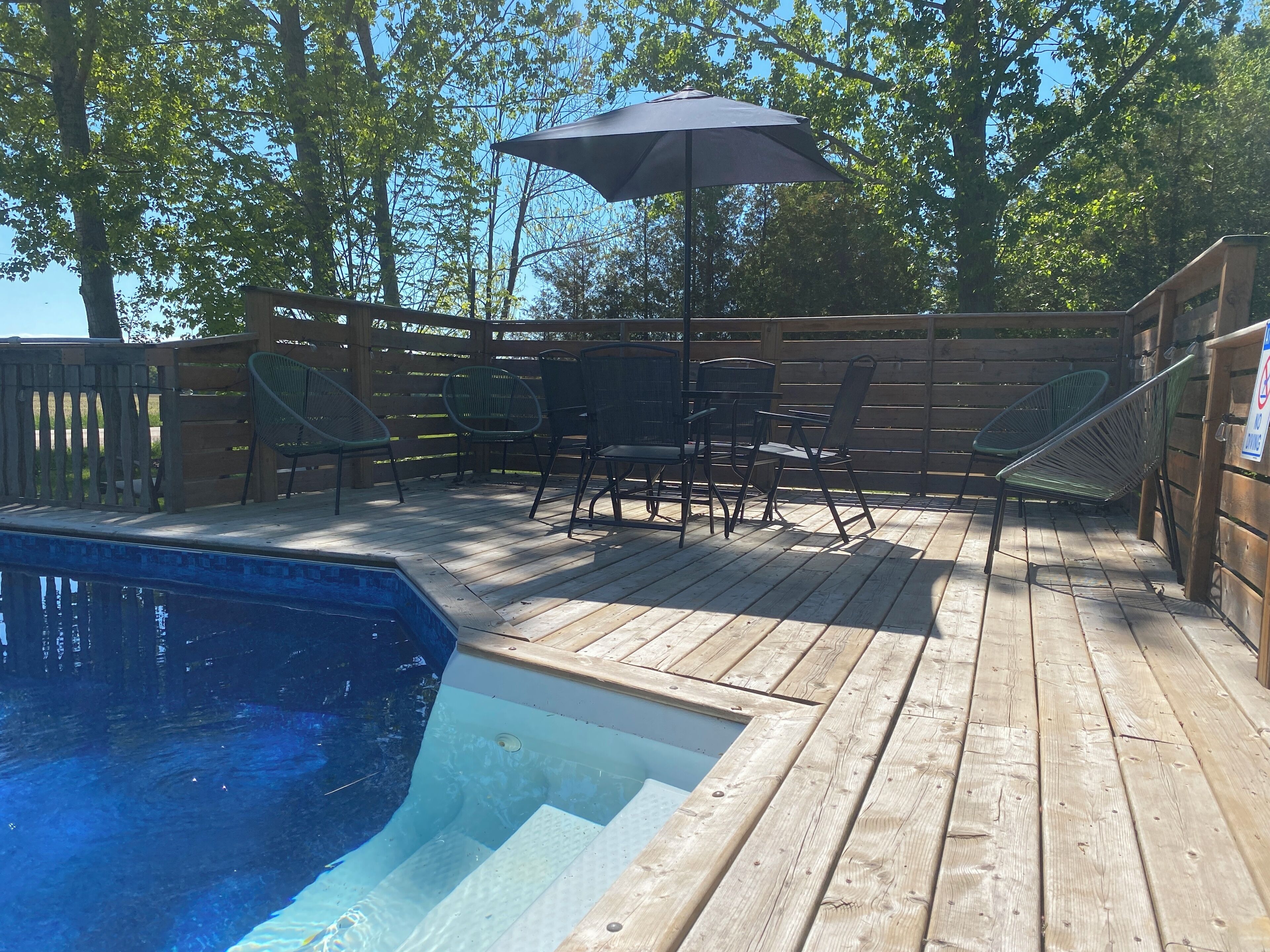 Una terraza de madera con piscina, muebles de exterior y valla de madera.