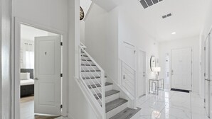 A modern interior with a staircase, white walls, and a clean, tiled floor. - Chic Modern Escape, 12BR, Pool and Game Room (Kissimmee)