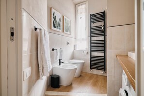 Een moderne badkamer met toilet, bidet en een zwarte handdoekhouder.