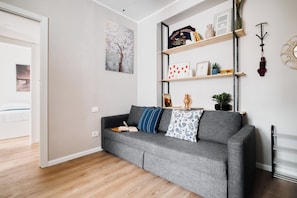 Un salon moderne avec un canapé gris, des étagères en bois et un radiateur.