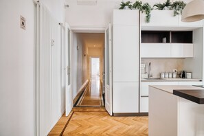 A modern kitchen with white cabinetry, a wooden herringbone floor, and a view into the adjacent living area. - Milano Isola Luxury Living; big Terrace (Milan)
