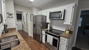 A kitchen with stainless steel appliances, a microwave, a dishwasher, and a coffee station.