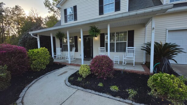 A two-story house with a covered porch, white exterior, and black shutters.