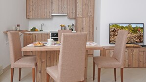 Eine moderne Küche mit Holzschränken, einem Esstisch mit vier Stühlen und einem Fernseher, der eine Berglandschaft zeigt.
