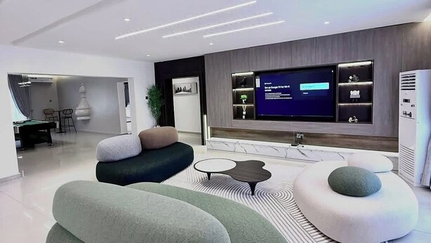 Un soggiorno moderno con una televisione a schermo piatto, posti a sedere confortevoli e un design minimalista.