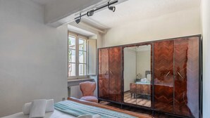 Un dormitorio con cama, armario, silla y ventana.