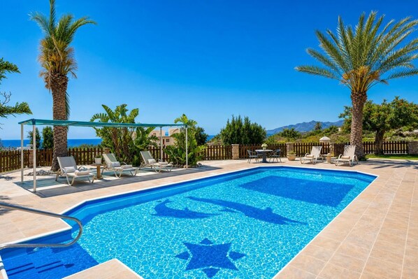 A swimming pool with lounge chairs, a pergola, and a view of the sea. - Villa Chrisandria - Three Bedroom Villa, Sleeps 6 (Argaka)