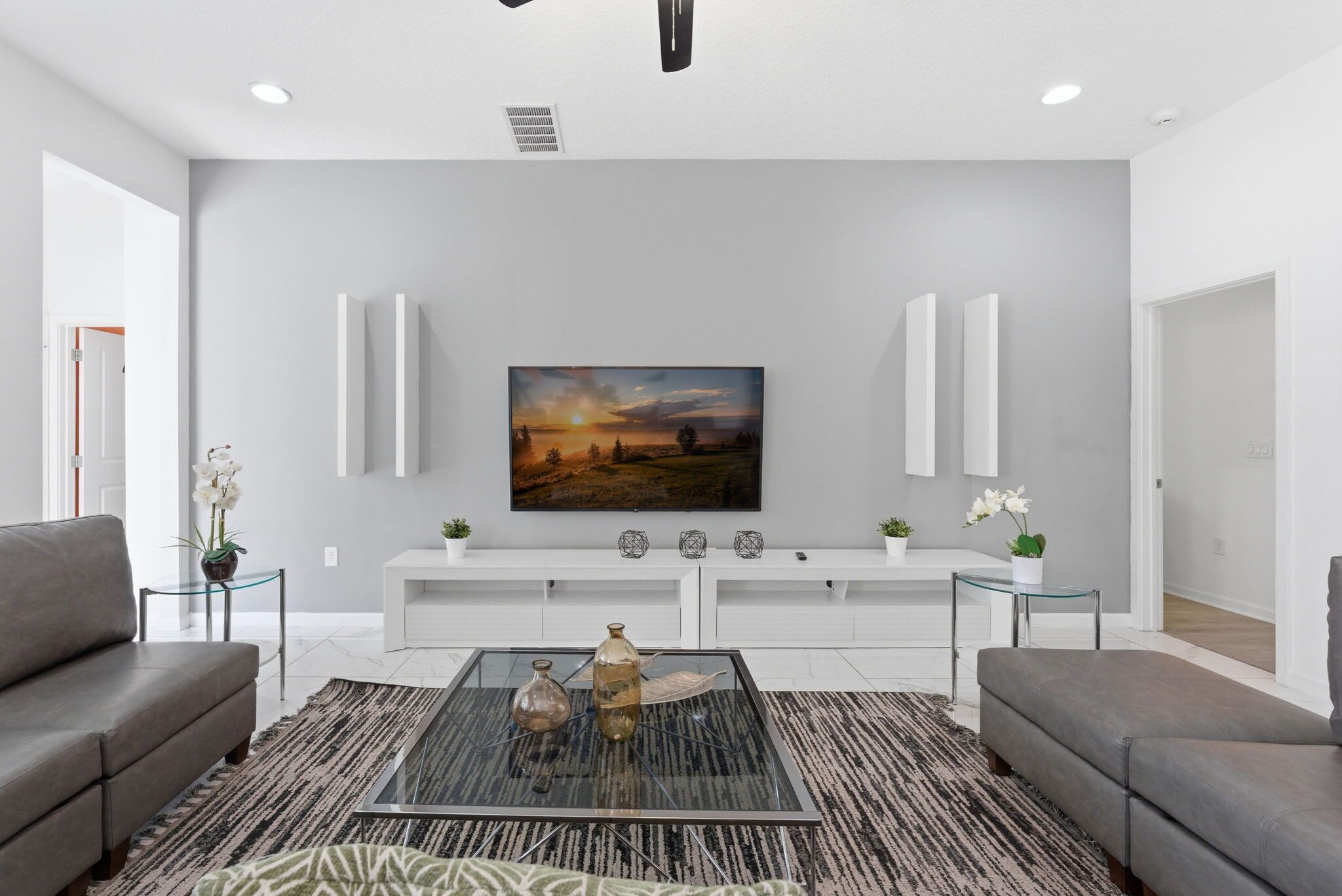 A modern living room with a large painting on the wall, a glass coffee table, and two sofas.