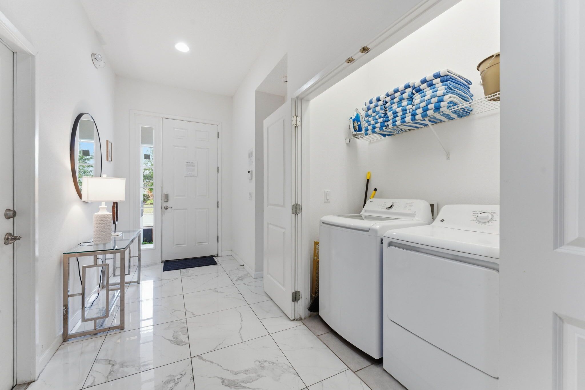 A clean, modern laundry room with a washing machine, dryer, and neatly folded towels on a rack.