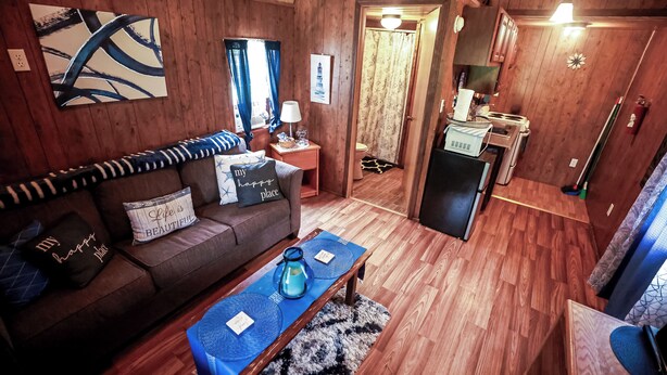 Una sala de estar acogedora con un sofá, una mesa de centro y una zona de cocina con refrigerador y estufa.