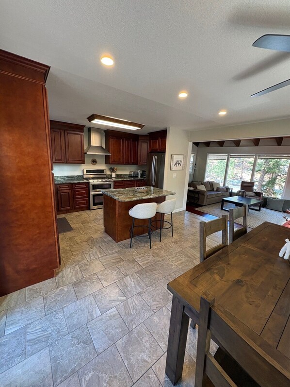 A modern kitchen with dark wooden cabinets, a granite countertop, and a central island with bar stools.