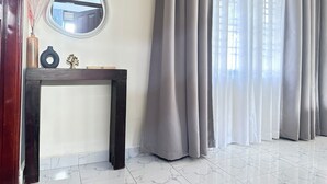 Una habitación con una consola de madera oscura, un espejo redondo y un florero con plantas secas.
