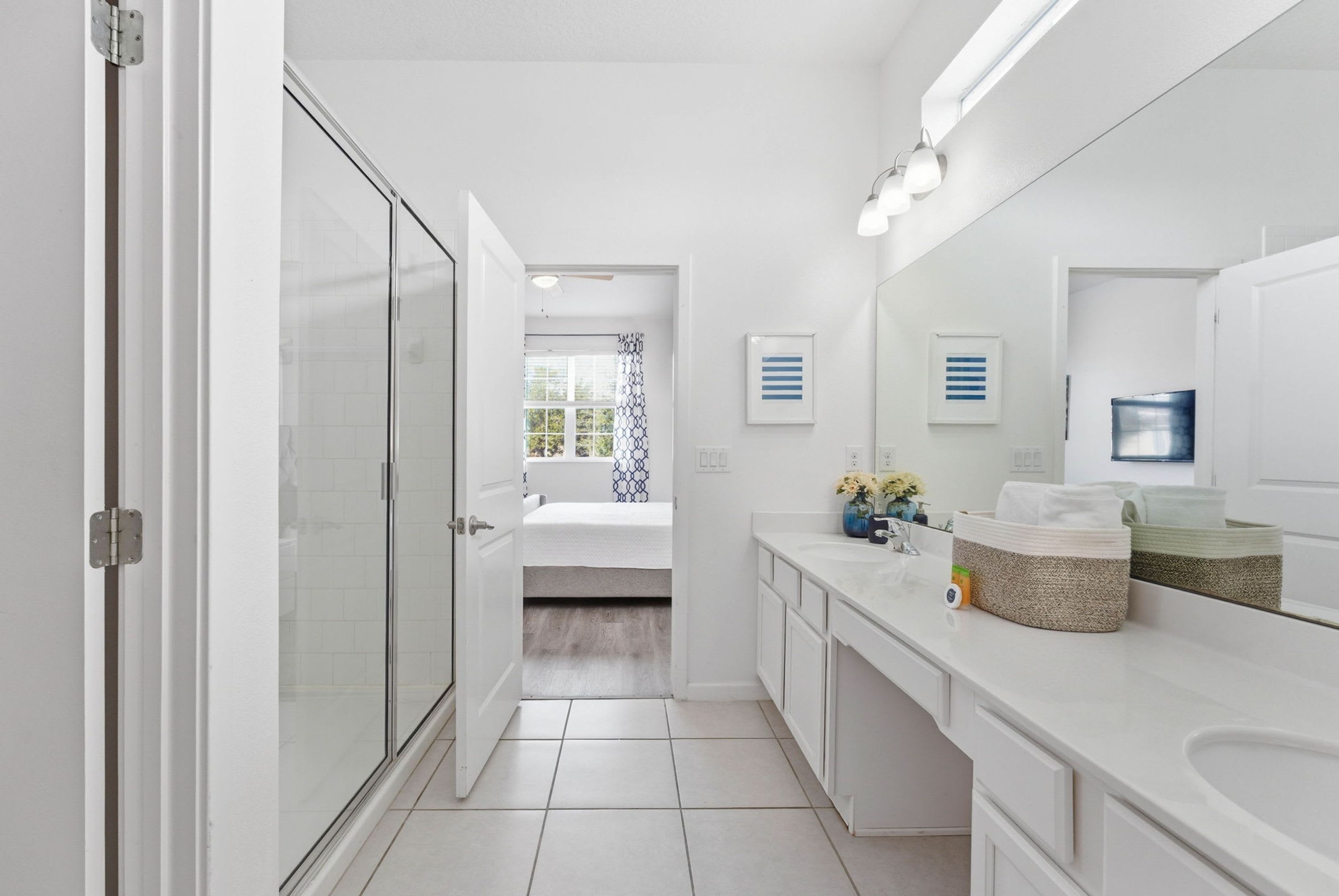 Une salle de bain moderne avec une douche à parois de verre, des meubles blancs et un grand miroir.