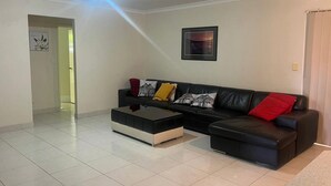 A modern living room with a black leather sofa, a coffee table, and a framed picture on the wall. - 10 mins drive to T4 terminal, walking distance to the Swan river! Family home. (Bayswater)