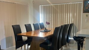 A dining area with a wooden table, black chairs, and a modern bar area. - 10 mins drive to T4 terminal, walking distance to the Swan river! Family home. (Bayswater)