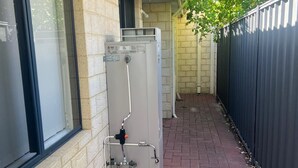 A building with a brick exterior, a window, and a water heater unit on the ground level. - 10 mins drive to T4 terminal, walking distance to the Swan river! Family home. (Bayswater)