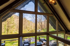 A room with large windows offering a view of a forested area and a mountain. - 5* Cabin~HotTub~FirePit~GameRm~PlayRm~Gburg7min (Gatlinburg)