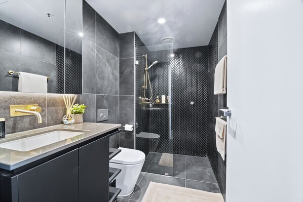 Un baño moderno con un lavamanos grande, inodoro y zona de ducha.