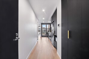 A modern hallway with a wooden floor, a black door on the left, and a black wardrobe on the right. - Elegant Top Floor 1BR, Sleeps 4, City Views (Reid)