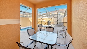 A glass-top table with four chairs, a pool, and a view of neighboring buildings. - Bright & Breezy Disney Escape | Pool | BBQ (Kissimmee)