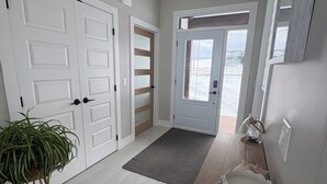 A hallway with white doors, a grey doormat, a wooden bench with decorative items, and a ceiling light fixture.