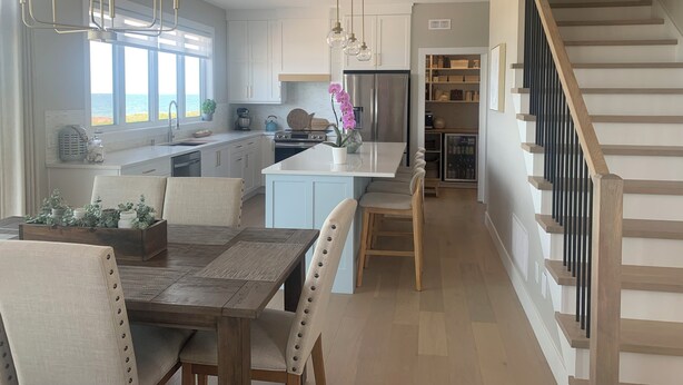 A modern kitchen with a central island, pendant lighting, and a view to the outside.