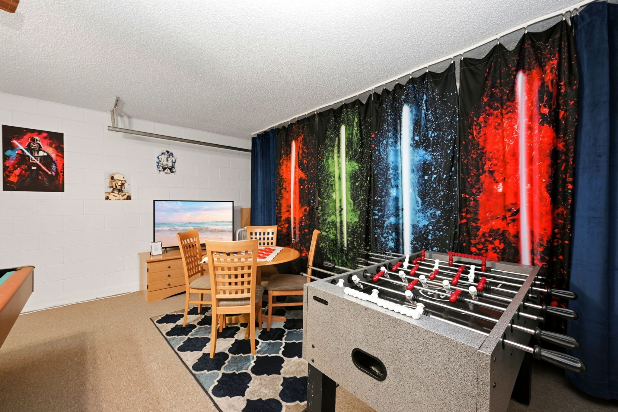 Ein Zimmer mit einem Kicker, einem Schreibtisch mit Computer und Wandgestaltung zum Thema Star Wars.