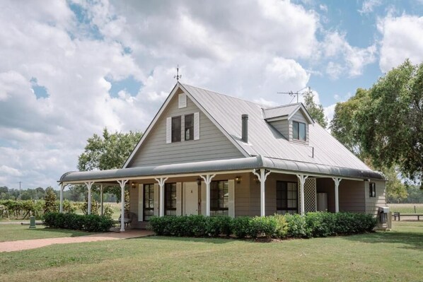 A two-story house with a covered porch, a chimney, and a satellite dish. - Emma's Cottage Vineyard (Lovedale)