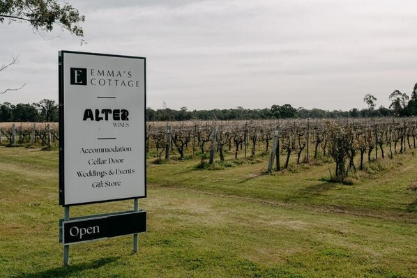 A sign for Emma's Cottage, listing services like accommodation, cellar door, weddings & events, and a gift store. - Emma's Cottage Vineyard (Lovedale)
