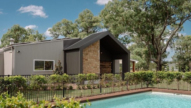 A modern house with a swimming pool, surrounded by a fence and trees.