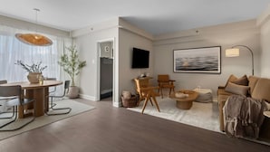 Una sala de estar moderna con comedor, televisor de pantalla plana en la pared y un ventanal con cortinas translúcidas.