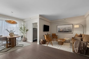 Ein modernes Wohnzimmer mit Essbereich, einem flachbildfernseher an der Wand und einem großen Fenster mit transparenten Vorhängen.