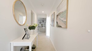 A hallway with a white console table, a mirror, and framed artwork.