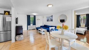A modern living room with a blue sofa, white dining table, and chairs. - Cozy Family Retreat Minutes From Falls  (Niagara Falls)